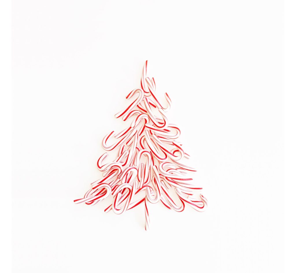 Christmas tree shape formed from red and white peppermint candy canes on a white background.