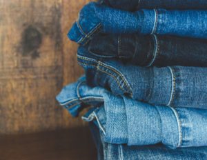 Close Up Shot of Blue Jeans in a Pile Against a Wooden Background