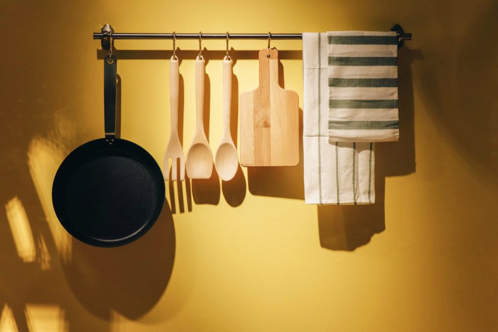 Kitchenware hanging on a yellow kitchen wall.