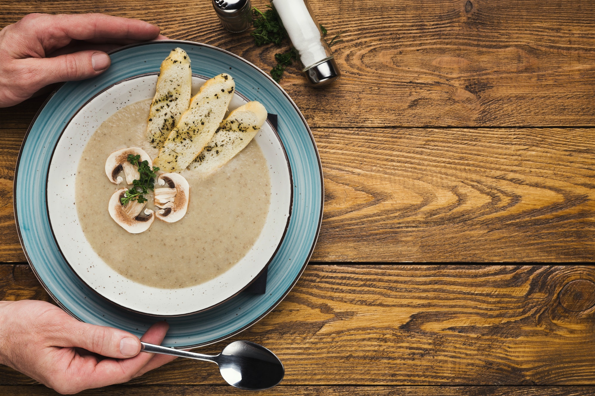 Male hands with mushroom cream soup, top view