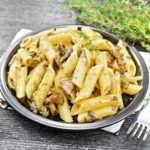 Pasta with mushrooms in plate on board